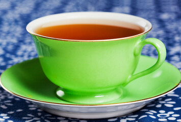 Close up of tea in a green porcelain teacup with matching saucer.