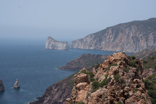A vast expanse of water bordered by rocky terrain and towering mountains