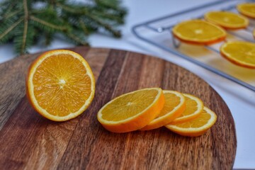 Slicing Orange on a wooden board for further drying on a baking sheet in the oven, for decoration.
