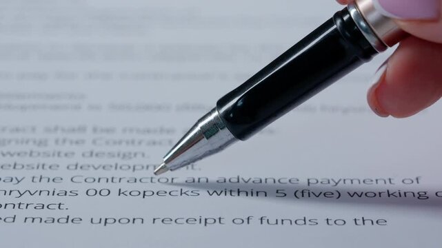 Close up shot of woman hand working with document, pen in female hand writing a personal signature in financial or business document.