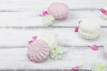 Fruit marshmallow with fresh flower petals on white wooden background. Lactose free vegan dessert