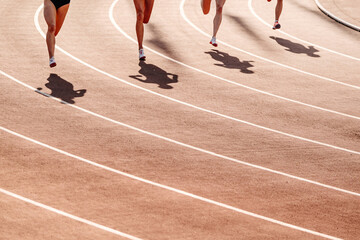 beginning 800-meter race, women legs, shadows on red track stadium