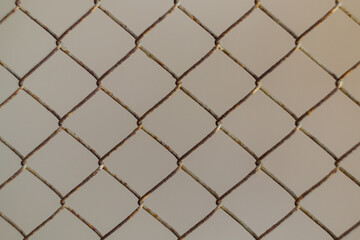Fototapeta premium An aged metal mesh netting with an uneven surface has corroded due to humidity in the air. Consequences of Neglecting the Importance of the Need to Paint Metal Surfaces in the Atmosphere