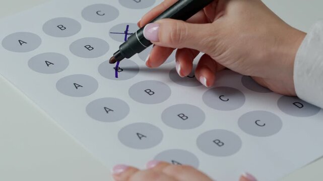 Close up shot of woman at the desk working with important exam document, student reading and picking answers in test, crossing out with marker letters questions.