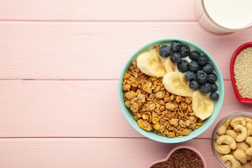 Oat raisin granola with fresh summer berries in a bowl on pink wooden background. Concept of healthy breakfast food, clean eating, dieting