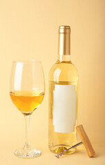 Unlabeled bottled of white wine with half empty wineglass standing on beige background. Vertical photo