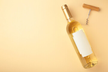 Bottle of exquisite wine and corkscrew on beige background