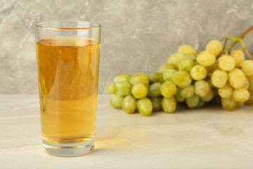 Glass of grape juice on light background. Green grape