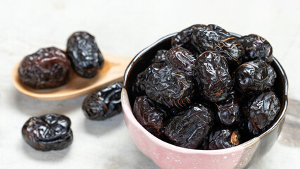 Ajwah dates in a ceramic bowl on a white wooden background are the best fruits of Medina.