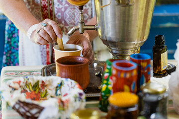 Copper samovar with white teapots and cup of herbal tea