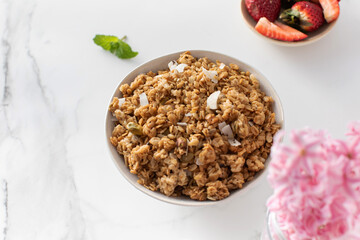 Crispy homemade granola with sliced almonds in a bowl with strawberries. Healthy eating