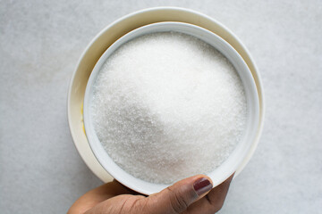 Overhead view of white sugar in a white bowl, top view of granulated sugar in a bowl