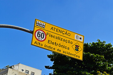 Traffic sign speed limit at 60 kilometers per hour and information in portuguese saying: Attention, electronic inspection, high accident rate