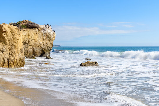 Waves crashing on a baech with large sea stacks on the coast of California on a clear autumn day