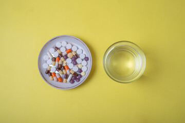 dietary supplements for weight loss and a glass of water top view on a yellow background