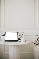 Laptop and white mug with tea on a table. Workspace in a modern room.