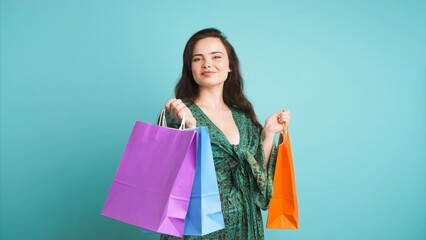 Happy woman showing shopping bags in blue studio