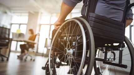Obraz premium Close-up of a person in a wheelchair in an office with colleagues in the background. Promotes workplace inclusion and diversity for disabled employees.