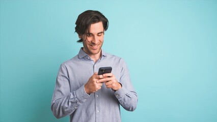 Happy adult man using smartphone in blue studio