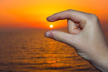 A Hand Holding the Sun at Sunset