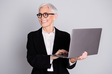 Portrait of successful gorgeous senior lady wear black trendy suit hold modern gadget look empty...