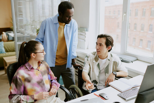 African American teamlead discussing new project with his female programmer and coworker with disability while he gesticulating