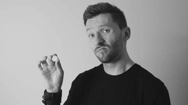 Footage of a man showing a 1 euro cent and feeling disappointed by it in slow motion. Video is shot in black and white and 4K.