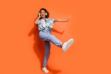 Photo portrait of brown wavy haired girl meloman wearing wireless headphones chilling out with music playlist isolated on orange color background