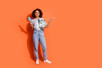Photo of brown haired curly girl in summer shirt holding mobile phone pointing finger new social...