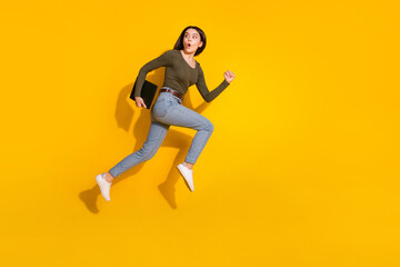 Fototapeta na wymiar Full body photo of attractive teen woman running scared turn around dressed stylish khaki clothes isolated on yellow color background