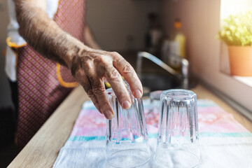 Senior bearded man washing dishes in domestic kitchen.