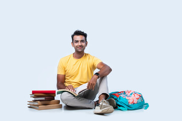 Asian Indian young college or university student studying while sitting on floor