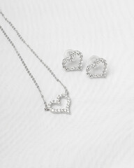 Silver jewelry in the shape of hearts on a white cloth. Elegant and stylish accessories, perfect for romantic and special occasions.