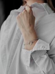 A woman's hand in a white shirt with a bracelet on her wrist. An elegant decoration with a minimalistic design, suitable for any occasion.