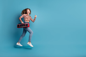 Full length portrait of nice young girl jump run boombox wear top isolated on blue color background