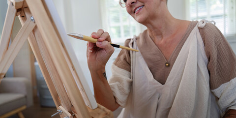 Senior Woman Painting on Canvas at Home in Bright Room with Natural Light