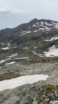 Lac blanc vu de haut, entour&eacute; par une montagne dont la pente est &agrave; moiti&eacute; enneig&eacute;e. La neige contraste avec les parties d&eacute;nud&eacute;es, cr&eacute;ant un paysage alpin spectaculaire et glac&eacute;.