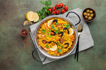 Traditional spanish seafood paella with rice, mussels, shrimps in a pan on wooden background. Top view. Flat lay