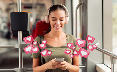 A woman wearing headphones smiles while using her smartphone on a bus or train. The screen is not visible, but she looks pleased as she navigates the digital world