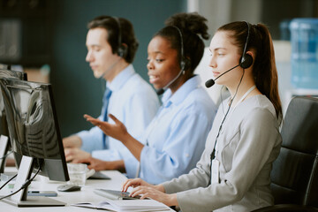 Team of young biracial operators having callsat work in office of modern company