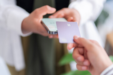 Close-up of a person using a credit card to make a payment via a mobile phone The phone displays the amount to be paid, showcasing a seamless transaction