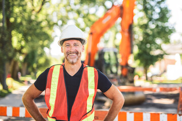 caucasian engineer with white helmet at work and having a mechanical shovel on the back