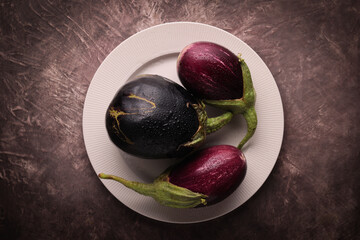 Composizione con melanzane fresche in un piatto: natura morta ripresa dall’alto