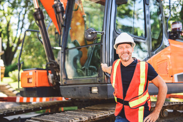 caucasian engineer with white helmet at work and having a mechanical shovel on the back