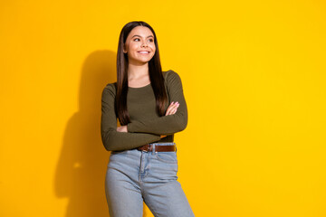 Photo portrait of pretty teenager girl look empty space crossed hands wear trendy khaki outfit isolated on yellow color background