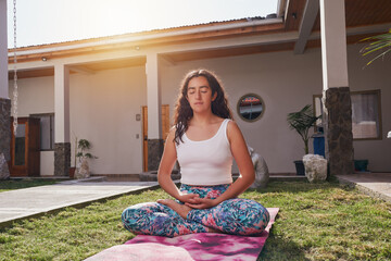 portrait latin woman meditating in lotus position in the patio of the house