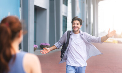 Fototapeta premium Wife meeting husband at airport terminal, welcoming back home. Man opening arms for hug