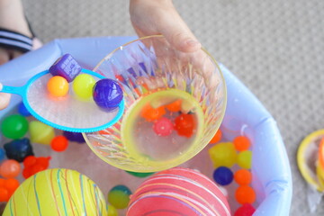 小学生の子供が庭でボールすくいを楽しんでいる様子。ポイの上にのっているスーパーボール。