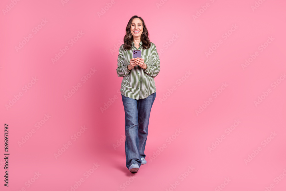 Sticker Full body portrait of pretty aged lady walk smart phone wear shirt isolated on pink color background