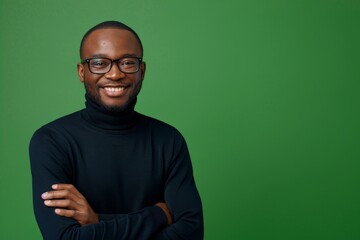 Fototapeta premium An African man stands against a green background and laughs confidently